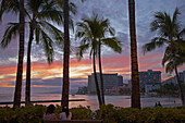 Menschen und Palmen am Waikiki Beach bei Sonnenuntergang, Honolulu, Oahu, Hawaii, USA, Amerika