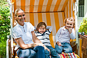 Mother with two children sitting in a roofed wicker beach chair, Hamburg, Germany