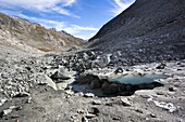 The glacier snout with ice cave of Viltragenkees in the National Park Hohen Tauern  Viltragenkees is showing signs of rapid retreat  Its snout is flat and covered with moraine The glacier foreland shows fresh moraine till  Mt Kleinvenediger in the backgro