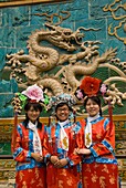 Girls in traditional costume pose in front of famous Nine Dragon Screen Wall in Beihai Park Beijing