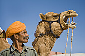 Man standing beside a camel at Osian Camel Camp, Osian, Rajasthan, India