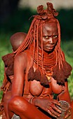 Himba woman with the baby on her back, near to Opuwo, Kaokoland, Namibia