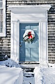 Christmas wreath on door with red bow and snow