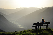 Frau sitzt auf einer Bank und genießt Aussicht auf Gschnitztal, Habicht, Gschnitztal, Stubaier Alpen, Tirol, Österreich