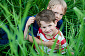 Zwei Jungen (6 - 7 Jahre) sitzen im Gras