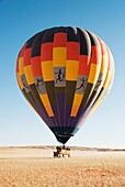 Namibia - After having landed, the ground crew pulls the basket with the passengers to the nearby truck, while the pilot skilfully keeps the hot-air balloon on the right height Namib Desert, NamibRand Nature Reserve, Namibia