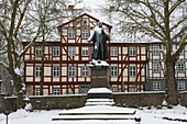 Snow covered monument of Lingg von Linggenfeld, founder of Bad Hersfeld, with timberframe house, Bad Hersfeld, Hesse, Germany, Europe