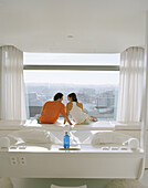 Paar entspannt sich und schaut aus dem Fenster, Zimmer im 8. Stockwerk, Gestaltung Kathryn Findlay, Hotel Silken Puerta America, Madrid, Spanien