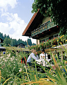 Couple sitting in the garden of organic Hotel Chesa Valisa, Hirschegg, Kleinwalsertal, Styria, Austria