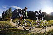 Mountainbiker auf der Rotwand im Sonnenlicht, Sexten, Hochpustertal, Südtirol, Dolomiten, Italien, Europa