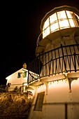 USA, California, Marin County, Point Reyes National Seashore, old lighthouse perched on point of Point Reyes Conglomerate rock, amateur photographers taking pictures, night, vertical