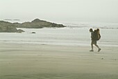 a lone hiker walks on the beach in the fog on Flores Island, Clayoquot Sound, British Columbia, Canada