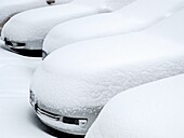 Parked cars buried in snow.