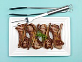 Cooked lamb chops on a plate isolated against a blue background