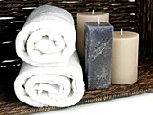 Scented candles in a basket with bath towels