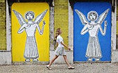 Woman walking near a wall painting with angels in Lisbon streets, Portugal, Europe