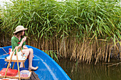 Girl wearing straw hat having a picnic in a boat on lake Teupitz, Brandenburg, Germany
