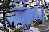 Zwei ältere Männer mit Hund auf einer Bank vor blauem Haus, El Sauzal,  Casa del Vino, Teneriffa, Kanaren, Spanien