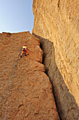 Woman climbing at red rock face, Great Spitzkoppe, Namibia