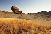 Balancing granite rock laying on slab, savannah gras in foreground, Bull´s Party, Ameib, Erongo mountains, Namibia