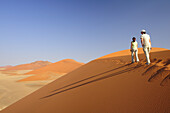 Two women walking on red sand dune in Sossusvlei, dune 45, Sossusvlei, Namib Naukluft National Park, Namib desert, Namib, Namibia