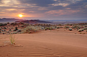 Sonnenaufgang über roter Sanddüne mit Tirasberge im Hintergrund, Namibwüste, Namibia