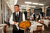 Waiter serving paella, restaurant La Pepica, Province Valencia, Valencia, Spain