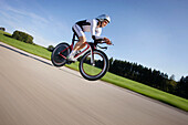 Male racing cyclist with disc wheel on road near Munsing, Upper Bavaria, Germany