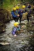 Young children walking in the River Arran near Dolgellau as part of a course organised by the Canolfan Yr Urdd outward bound adventure centre, Glanllyn, Bala, North Wales UK