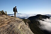 A hiker takes in the view of undercast from the summit of Mount Osceola in the White Mountains, New Hampshire USA