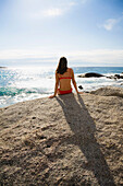 Woman sunbathing on a rock, bay of Algajola, Corsica, France