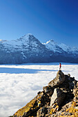 Woman standing on rock and looking towards Eiger and Jungfrau above sea of fog, Bussalp, Grindelwald, UNESCO World Heritage Site Swiss Alps Jungfrau - Aletsch, Bernese Oberland, Bern, Switzerland, Europe