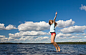 Nine year old girl jumping in the air at Boasjön lake, Smaland, South Sweden, Scandinavia, Europe