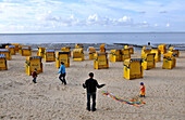 Familie spielt mit einen Drachen am Strand von Cuxhaven, Nordseeküste, Niedersachsen, Deutschland