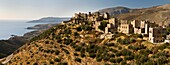 The village of Vathia with its many tower houses and the dramatic coast of the Deep Mani in the background, Southern peloponnese, Greece