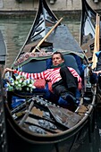 Gondolier sleeping in his gondola on canal in Venice Italy