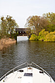 Bow of the houseboat navigating under a roofed bridge near Ahrensberg, Mecklenburgian Lake District, Mecklenburg-Pomerania, Germany