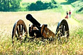 Cannon in hay field on Battle of the Boyne site at Oldbridge, near Drogheda, County Meath Couple walking hand in hand behind