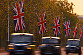 Black cabs driving along The Mall at dusk, London, UK - England