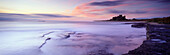 Bamburgh Castle and the Farne Islands at dawn at high tide, Bamburgh, Northumberland, UK - England