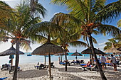 Palmen und Menschen am Strand des Beachcomber Hotel Paradis &amp; Golf Club, Mauritius, Afrika