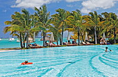 People and palm trees at the pool of Beachcomber Hotel Paradis &amp; Golf Club, Mauritius, Africa