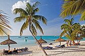Palm trees and people on the beach of Beachcomber Hotel Paradis &amp;amp;amp; Golf Club, Mauritius, Africa