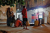 Local people watching TV in an alley of Stonetown, Zanzibar City, Zanzibar, Tanzania, Africa