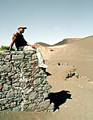Labourer sitting on a wall, former village has been buried by a vulcanic eruption in 1958, Vulcao dos Capelinhos, Faial island, Azores, Portugal