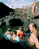 Azorean family bathing in igneous rock pool, near Mosteiros, western shore of Sao Miguel island, Azores, Portugal