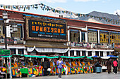 Läden mit Gebetsfahnen am Barkhor Platz in der Altstadt von Lhasa, Potala Palast im Hintergrund, autonomes Gebiet Tibet, Volksrepublik China