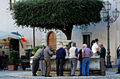 Men standing around the fountain and chatting, Pitigliano, Tuscany, Italy