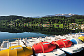 Bunte Tretboote am Millstätter See mit schneebedeckten Bergen im Hintergrund, Seeboden, Millstätter See, Kärnten, Österreich, Europa
