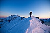 Person hikes along snow covered ridge of Stamsundheia with Steinstind peak in distance, Stamsund, Vestvågøy, Lofoten islands, Norway